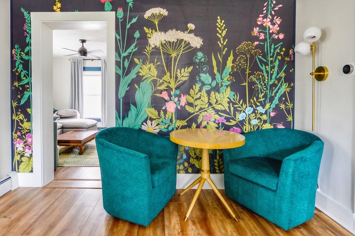 Step into a space where art meets comfort. This cozy sitting area features bold botanical wallpaper, plush seating, and warm natural light—perfect for morning coffee or evening wine. Thoughtfully designed to feel inviting, stylish, and like home.